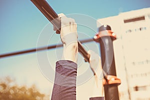 Closeup of a teenager`s hands on a horizontal bar. Pulling on the crossbar. Vintage toning