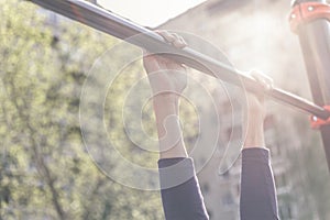 Closeup of a teenager`s hands on a horizontal bar. Pulling on the crossbar. Vintage toning