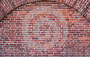 Texture of an old red brick wall with the semicircular arch in brickwork as an old-fashioned architectural background