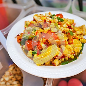 Thai street food, Spicy fruits salad mixed with corn and tomato on white plate-soft focus