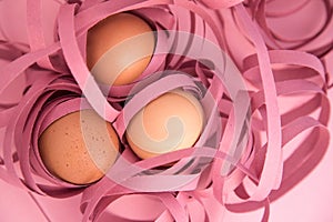 Closeup of three eggs wrapped in colored ribbons. Fragility and protection concept.