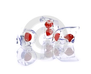 Closeup of three ice cubes with cherries inside isolated on a white background