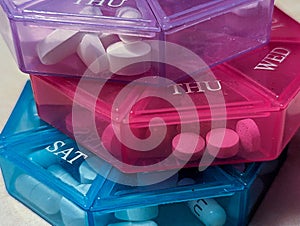 Closeup of three pill sorters filled with pills