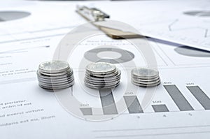 Closeup of three stacks of silver coins on the graphs and business charts.Concept of financial analyzing of budget and sales