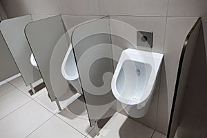 Closeup of three white urinals in men`s bathroom design of white ceramic urinals for men in toilet room, Loft wall