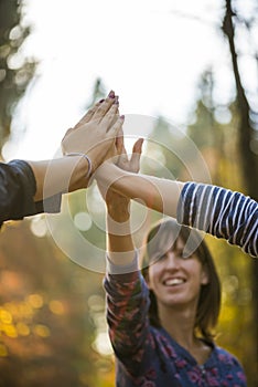 Closeup of three women joining hands high up in the air