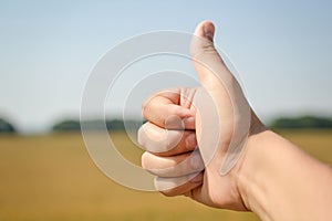 Closeup of thumb up hand on sunny day outdoors background, picture close up