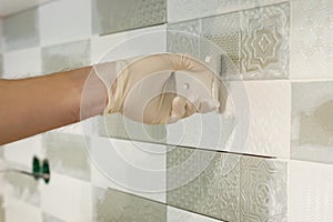 Closeup of tiler hand rubbing tile, Installing and grouting decorative finishes in environments with an high aesthetic value. Two-