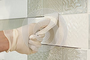 Closeup of tiler hand rubbing tile, Installing and grouting decorative finishes in environments with an high aesthetic value. Two- photo