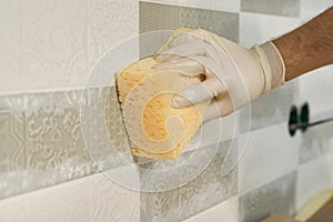 Closeup of tiler hand rubbing tile, Installing and grouting decorative finishes in environments with an high aesthetic value. Two-