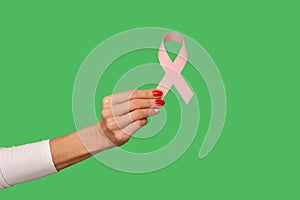 Closeup of tiny female hand with manicure holding pink ribbon, symbol of breast cancer awareness