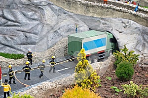 Closeup of tiny model firemen rescuing a truck stuck under a bridge
