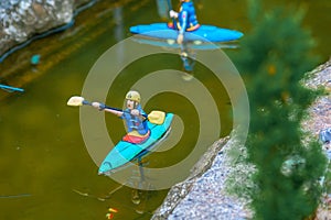 Closeup of tiny model people kyaking on a river
