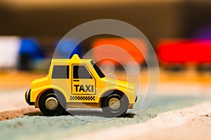 Closeup of a tiny taxi car toy on a wooden table on a blurry background