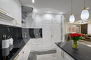 Closeup to black granite worktop of white domestic kitchen with marble floor