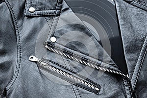 Closeup to a black leather biker jacket with LP vinyl disc.