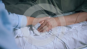 Closeup to the camera capturing video in the hospital old man laying down on the bed and wearing finger heart rate while