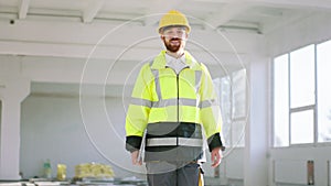 Closeup to the camera charismatic man architect holding laptop and analysing the plan of construction at construction