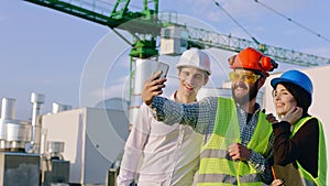 Closeup to the camera group of charismatic diverse specialists on the top of construction site wearing safety helmets