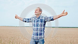 Closeup to the camera smiling and happy farmer man walking through the wheat field and feeling freedom and happy. Shot