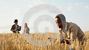 Closeup to the camera taking video from the back walking through the large wheat field man farmer and take his hat off