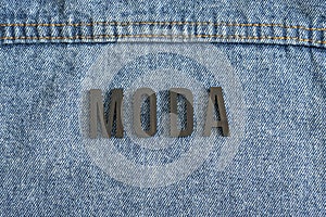 Closeup to a fashion word in spanish `MODA` lettering black word over a gradient Blue jean photo