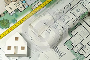 Closeup to floor plans, white paper house, measuring yellow tape. Architect drawings, expensive renovation,  building construction