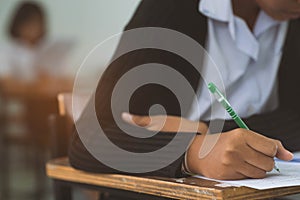 Closeup to hand of student  holding pen and taking exam in classroom with stress for education test