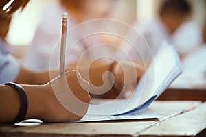 Closeup to hand of student  holding pencil and taking exam in classroom with stress for education test