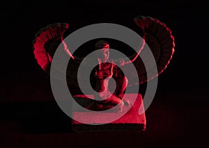 Closeup to a Isis. female old winged egyptian god mini figurine iluminated with red lights