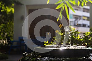 Closeup to little fountain from bamboo stick inside green vintage jar that decorated in the garden with sunlight effect