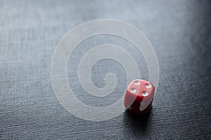 Closeup to a lonely red dice over a black background.