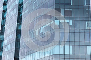 Closeup to a modern blue skyscraper windows reflection white clouds and sky