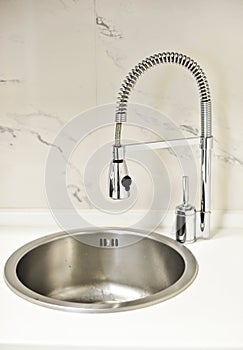 Closeup to a modern stainless steel kitchen sink .