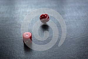 Closeup to a red dices, one dice is spinning over a black background.