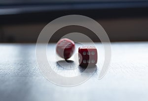 Closeup to a red dices, one dice is spinning over a black background.