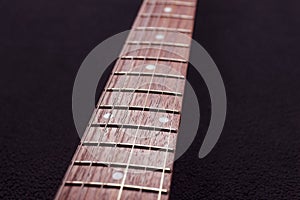 Closeup to a six electric guitar strings and wooden fretboards