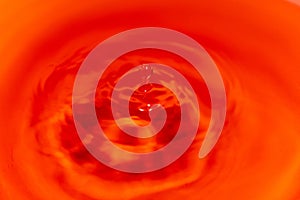 Closeup to water drops making circles on the surface. Amazing red color background. Natural beauty.