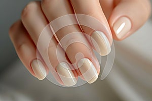 Closeup to woman hands with elegant neutral colors manicure. Beautiful ivory nude gel polish manicure on long square