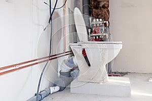 Close-up toilet on the block of aerated concrete on  floor against  background construction in bathroom, water copper and sewer