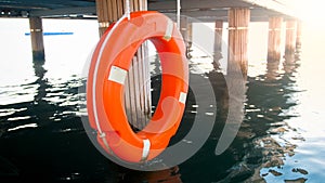 Closeup toned image of orange life saving buoy hanging at wooden pier