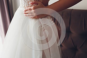 Closeup toned photo of beautiful bride tying up her wedding dress.