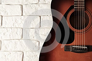 Closeup toned view of acoustic guitar with a white bricks background