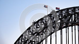 Closeup of the top of Sydney Harbour Bridge with waving Australian flags