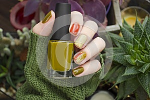 CloseUp top view of beautiful faded colors trendy manicure of green and beige glossy nails. Winter or autumn style of nail design