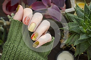 Closeup top view of beautiful faded colors trendy manicure of green and beige glossy nails. Winter or autumn style of nail design