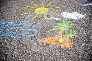 Closeup top view of child`s chalk drawing of tropical beach. Blue sea water, yellow sun, sandy island with green palms growing