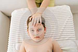 Closeup top view of cute five year old boy laying on bed at manual therapist in osteopath cabinet receiving manual
