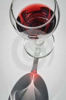 Closeup top view of a glass of red wine with shadows and reflections