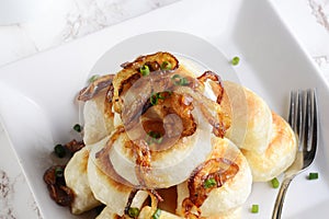 Closeup top view pierogies with caramelized onions and a fork